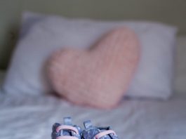 Children's Shoes And Clothes On The Bed. Beautiful Pink Baby Clo
